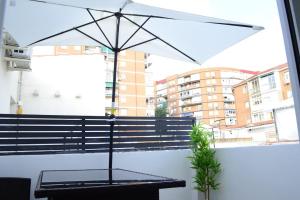 a table with an umbrella in front of a window at Casa en alquiler vacacional en Alcalá de Henares in Alcalá de Henares