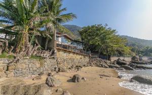 a house on the shore of a rocky beach at Refúgio da Arara in São Sebastião