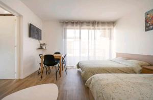 a bedroom with two beds and a desk and a window at Studio, Centre-Ville T1 in Annemasse