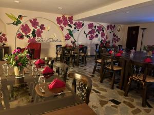 ein Restaurant mit Tischen, Stühlen und Blumen an der Wand in der Unterkunft Di Carbone Hotel Gastrobar in Facatativá