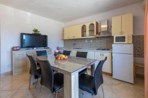 eine Küche mit einem Tisch und Stühlen sowie einem TV in der Unterkunft Apartment Silvana in Dramalj + 4 Fotos