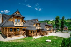 a large wooden house with a black roof at DOMKI Szarotka, Rozeta i Parzenica in Ratułów