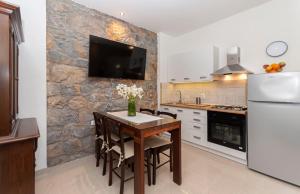a kitchen with a table and a tv on a stone wall at Apartment Feel the nature in Slime