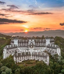 a large white building with a sunset in the background at Apartamento no Home Green Home - Vista para a montanha in Campos do Jordão