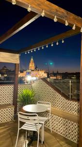 een tafel en stoelen op een balkon in de nacht bij Casón De Los López Apartments in Toledo