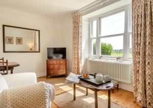 a living room with a couch and a window at Lodge Farm Cottage in Sudbourne