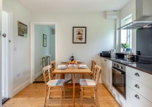 a kitchen with a wooden table and chairs in a kitchen at Lodge Farm Cottage in Sudbourne