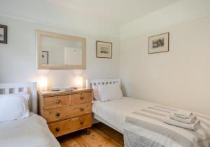 een slaapkamer met 2 bedden en een dressoir met een spiegel bij Lodge Farm Cottage in Sudbourne