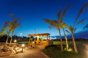 a gazebo with a table and palm trees at night at Villa Santo Spirito a 5 minuti da Otranto in Otranto