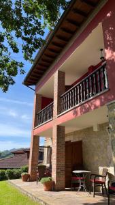 ein Haus mit einem Balkon, einem Tisch und Stühlen in der Unterkunft Apartamentos El Picoretu in Mestas de Con
