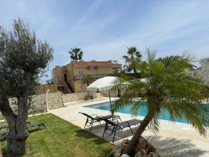 een villa met een palmboom en een zwembad bij Appartamenti - Villa Merilusi in Fontane Bianche