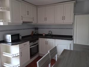 a kitchen with white cabinets and a table with a microwave at Casa de aldea La Caramba in Lamuño