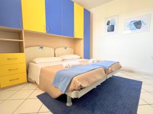 a bedroom with a bed with blue and yellow cabinets at Re del MARE - 3 BR Apt - Lounge con vista da SOGNO in Porto Recanati