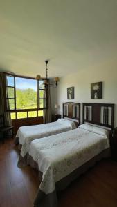 2 Betten in einem Zimmer mit einem großen Fenster in der Unterkunft Apartamentos El Picoretu in Mestas de Con