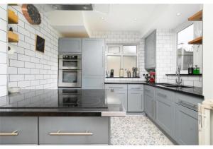 une grande cuisine avec des appareils blancs et des placards gris dans l'établissement lovely 2BR house in Orpington, à Orpington
