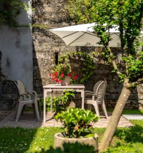einen Tisch und Stühle mit einem Regenschirm und Blumen in der Unterkunft Villa Trevisi - APARTMENT in Treviso