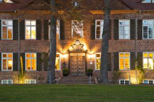 ein Backsteinhaus mit einer Eingangstür und Bäumen in der Unterkunft Romantik Hotel Gutshaus Ludorf in Ludorf