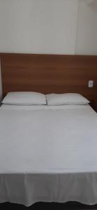uma cama com lençóis brancos e uma cabeceira de madeira em Flat Vista Mar em Boa Viagem em Recife mais 24 fotografias