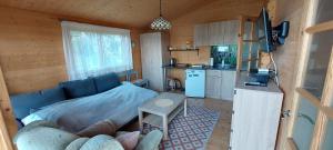 a living room with a blue couch and a kitchen at Lemanka Domek Letniskowy in Gowidlino