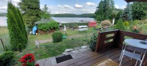 a deck with a view of a backyard with a lake at Lemanka Domek Letniskowy in Gowidlino