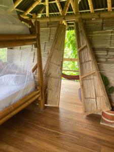 Habitación de planta abierta con cama y suelo de madera. en Finca La Selvita, en Buritaca
