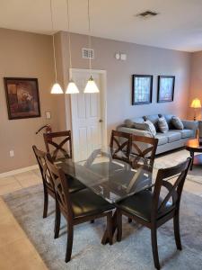 a dining room with a glass table and a couch at Orlando Disney Holiday Palace in Orlando