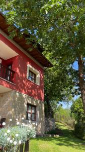 ein rotes Gebäude mit zwei Fenstern und einem Baum in der Unterkunft Apartamentos El Picoretu in Mestas de Con