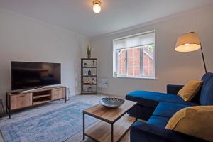 a living room with a blue couch and a tv at The Sycamores Country Escape in Marthall