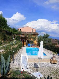 a swimming pool with two chairs and a umbrella at Casetta nel Podere di Massi in Barberino di Mugello