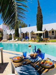 a table with food on it next to a swimming pool at L' Ecrin de Mogador Essaouira in Ounara