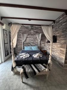 a bedroom with a canopy bed with a brick wall at SunnySun Studios in Faliraki