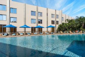 a hotel swimming pool with chairs and blue umbrellas at Radisson Blu Hotel Lusaka in Lusaka