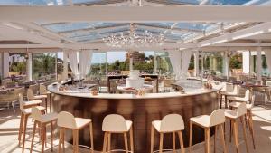 a restaurant with a bar with white chairs and tables at Steigenberger Hotel and Resort Camp de Mar in Camp de Mar