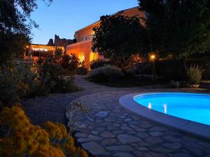 uma piscina num jardim à noite em Villa Cesarica Novalja em Novalja