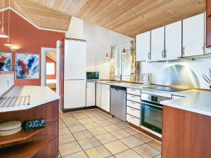 eine große Küche mit weißen Geräten und Holzdecken in der Unterkunft 10 person holiday home in Bl vand in Blåvand