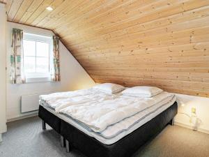 ein großes Bett in einem Zimmer mit einer Holzwand in der Unterkunft 10 person holiday home in Bl vand in Blåvand