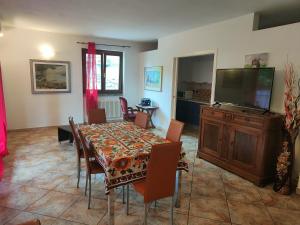 a dining room with a table and a flat screen tv at House curti in Sorico