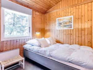 a bedroom with a large bed in a wooden wall at Holiday home Strandby XIII in Strandby