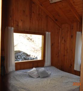 a bedroom with a bed with a window at Armonia de la Naturaleza in San Martín de los Andes