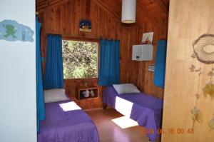 sypialnia z 2 łóżkami i oknem z niebieskimi zasłonami w obiekcie Armonia de la Naturaleza w mieście San Martín de los Andes