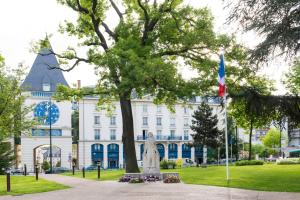 a statue in front of a white building with a tree at Le Plessis Grand Hotel in Le Plessis-Robinson