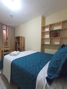 a bedroom with a bed with a blue blanket at Hotel Cuencano Hogar in Cuenca