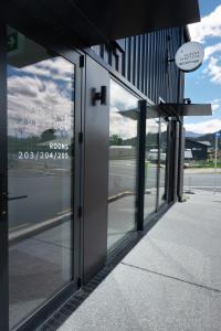 uma entrada para um edifício com portas de vidro em Alpine Junction Townhouse Apartments, Lodge & Hotel em Wanaka
