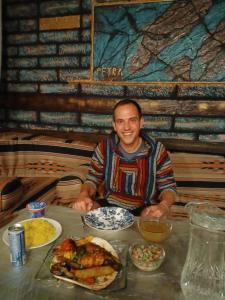 un hombre sentado en una mesa con platos de comida en Petra Anas House, en Wadi Musa