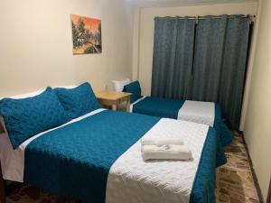a bedroom with two beds with blue and white sheets at Hotel Cuencano Hogar in Cuenca