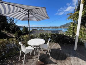 a table and two chairs and an umbrella on a deck at Serendipity Adorable Tairua Studio in Tairua