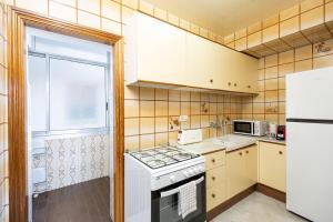una piccola cucina con piano cottura e frigorifero di Cozy Apt In Cornella 2 Mins From The Metro a La Gabarra
