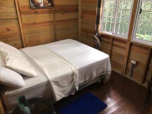 ein Schlafzimmer mit einem Bett mit weißen Laken und zwei Fenstern in der Unterkunft Hermosa Cabaña en Marbella!Omoa, Cortès in Omoa + 16 Fotos