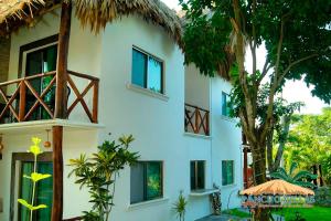 a white building with windows and a tree at Hotel Pancho Villas Bacalar - Gratis Renta Kayyaks in Bacalar