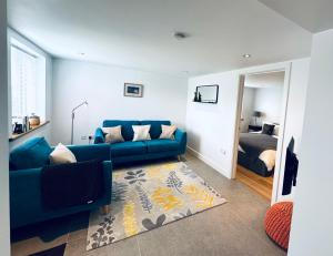 a living room with a blue couch and a bed at The West Wing in Devizes